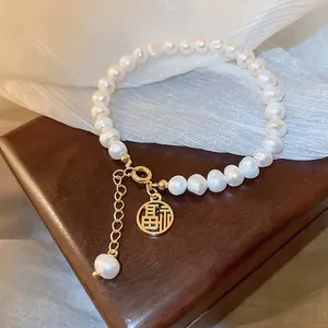 Detailansicht handgefertigtes Perlenarmband mit goldenem Fu-Charakter-Anhänger