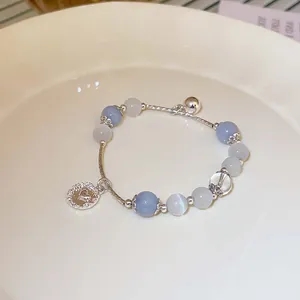 Detailansicht eines handgefertigten Perlenarmbands mit blauen Perlen und Herzanhänger in Schale.