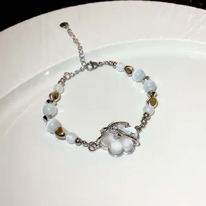 Detailansicht eines handgefertigten Perlenarmbands mit weißen Perlen und Blumenanhänger