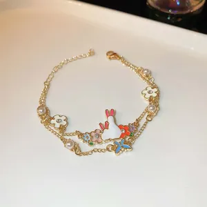 Detailaufnahme eines doppellagigen Goldarmbands mit Hasen-, Blumen- und Perlenanhängern.