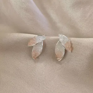 Nahaufnahme eleganter Kristall-Blütenohrstecker mit rosa Steinen auf weichem Stoff