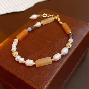 Makroansicht eines handgefertigten Perlenarmbands mit orangefarbenen rechteckigen Edelsteinen.
