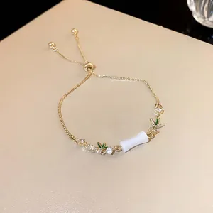 Detailansicht eines goldenen Armbands im chinesischen Stil mit Bambusanhänger und Blättern