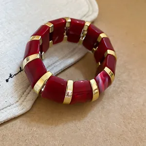 Red marbled acrylic bracelet with gold-toned spacers, elegant and minimalist design.