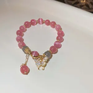 Detailansicht eines handgemachten Armbands mit rosa Katzenaugenperlen und Schmetterling.