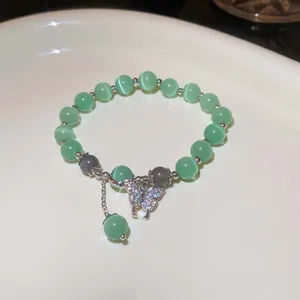 Exquisite Nahaufnahme eines grünen Perlenarmbandes mit einem funkelnden Schmetterlingsanhänger