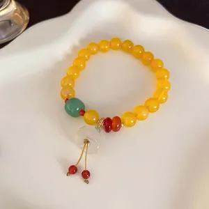 Detailansicht eines handgefertigten Perlenarmbands mit gelben Perlen und einem weißen Anhänger