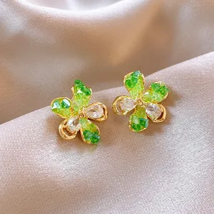 Nahaufnahme von eleganten Blumensteckern mit grünen und weißen Kristallen in Goldfassung.