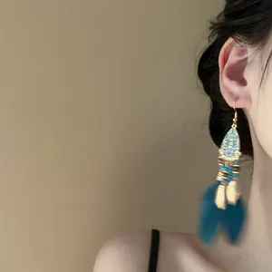 Eleganti orecchini a goccia bohémien con nappe di piume blu indossati per un look vintage