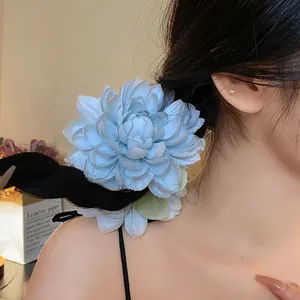 Vista dettagliata di una grande clip per capelli a fiore in tessuto blu chiaro indossata