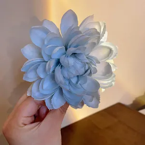 Primo piano di una delicata clip per capelli a fiore in tessuto azzurro con petali a strati