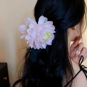 Primo piano di un fermaglio per capelli a fiore di stoffa rosa su capelli neri.