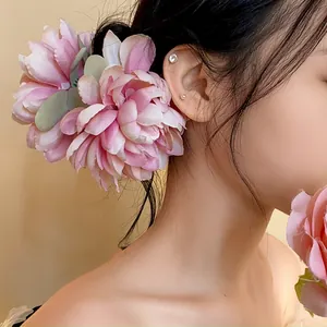 Dettaglio di una grande clip per capelli a forma di fiore in tessuto rosa su un'acconciatura