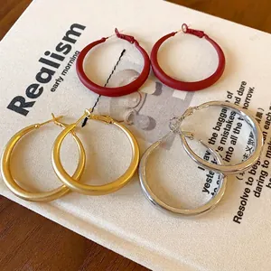 Minimalist geometric hoop earrings set in red matte, gold, and polished silver finishes