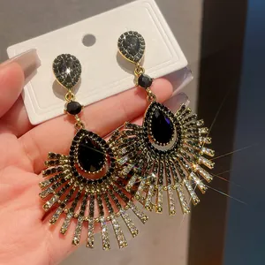 Close-up detail of luxury waterdrop fringe earrings with black rhinestones and gold finish.