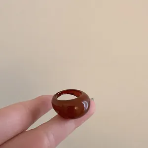 Close-up of a vintage brown resin geometric ring with a glossy finish on a finger
