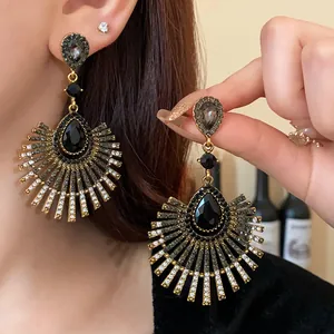 Close-up of vintage sunburst earrings with black teardrop rhinestones and gold-tone finish