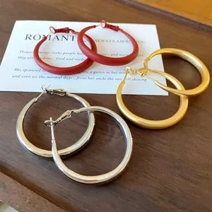 Close-up of minimalist geometric hoop earrings in red, gold, and silver finishes