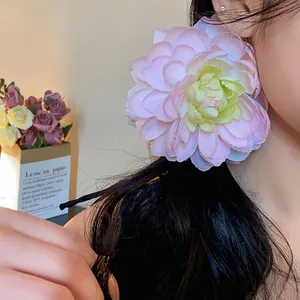 Dettaglio di un grande fermaglio per capelli a fiore rosa su una coda di cavallo.