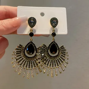 Detailed view of elegant gold-tone teardrop tassel earrings with black stones and rhinestones.