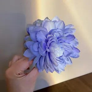 Dettaglio di una grande molletta per capelli a fiore in tessuto blu con petali ricchi