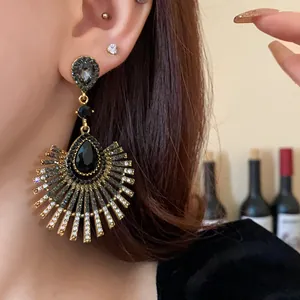 Close-up of elegant gold earrings with black teardrop rhinestones and radiating fringe