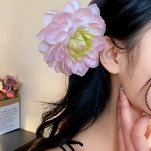 Dettaglio ravvicinato di una grande molletta a fiore in tessuto rosa indossata da una modella.