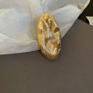 Close-up of a vintage golden geometric ring with a center pearl and textured shell design