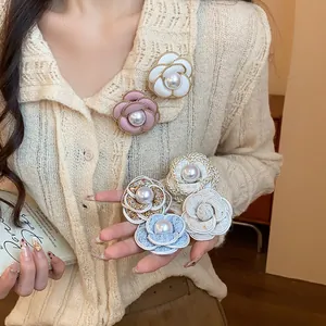 Detail of elegant camellia brooches with pearls in various colors and fabrics.