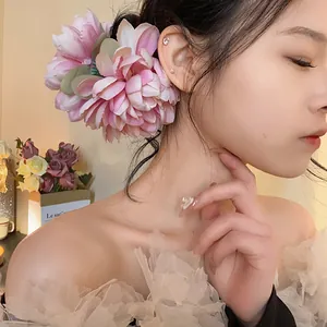 Primo piano di un'elegante molletta a forma di fiore rosa indossata su uno chignon basso.
