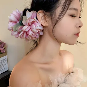 Vista laterale dettagliata di un'elegante pinza per capelli a fiore in tessuto rosa da donna