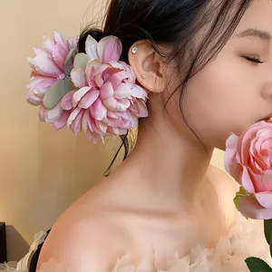 Vista laterale di un'elegante molletta per capelli con fiore in tessuto rosa su modella