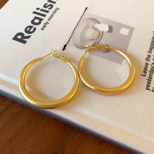 Close-up of matte gold hoop earrings with silver needles on a vintage book