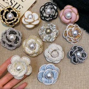 Close-up of elegant camellia brooches featuring pearl and tweed fabric textures