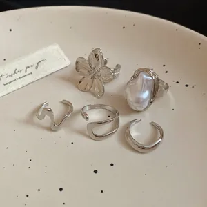 Macro detail of five vintage silver-toned rings displayed on a cream ceramic plate