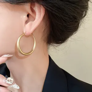 Detailed wearing shot of minimalist matte gold geometric hoop earrings with silver needles
