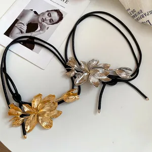 Detail view of gold and silver metal tulip flower ornaments on black leather waist chain.