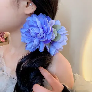 Primo piano di una grande molletta per capelli a forma di fiore blu su lunghi capelli neri