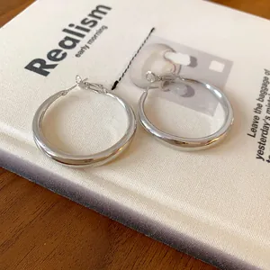 Close-up of minimalist silver hoop earrings with a polished finish on a book background