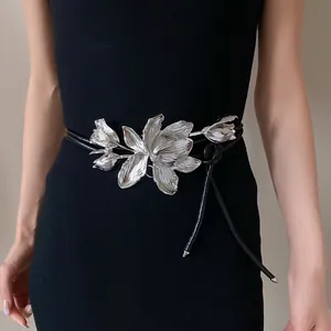 Detailed view of a metallic tulip waist belt on a black dress, highlighting floral design.