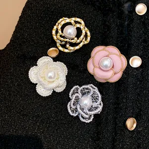 Detailed view of four elegant camellia flower brooches with pearls on black tweed jacket