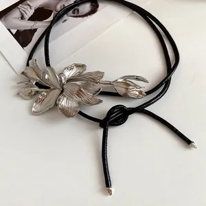 Detailed view of silver metal tulip flower design on a black leather waist chain