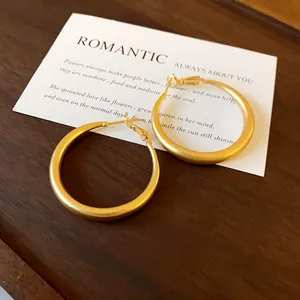 Detailed macro view of matte gold thick hoop earrings for a minimalist fashion style