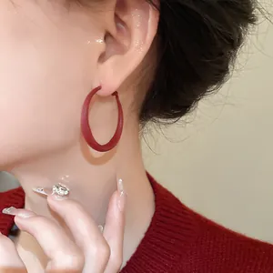Detailed close-up view of a minimalist red matte geometric hoop earring worn by a model.
