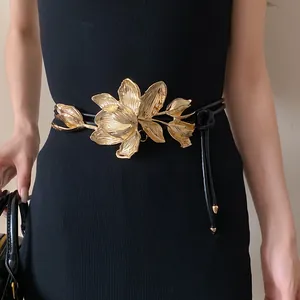 Close-up of golden tulip metal buckle on black leather belt with exquisite floral details