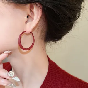 Detail view of stylish minimalist red matte geometric hoop earrings worn by an Asian model