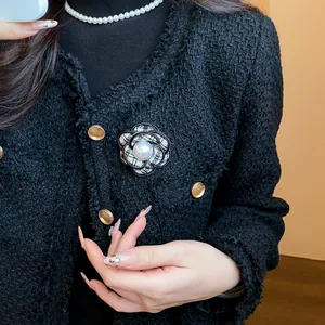 Close-up of a French style camellia brooch with pearl on a black tweed jacket