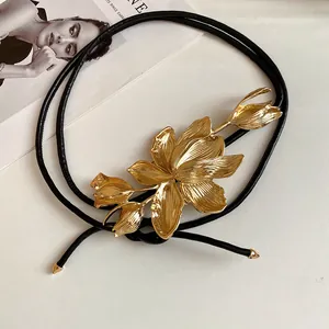 Detailed view of a vintage gold tulip metal flower on a black leather waist chain belt.