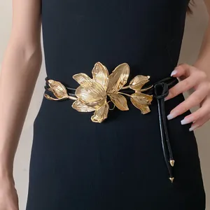 Close-up detail of a vintage golden tulip metal ornament on a black leather belt