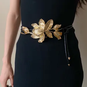 Detailed view of luxury golden tulip flower buckle on slim black leather waist belt